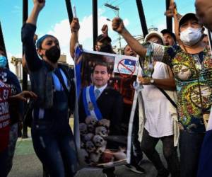 Supporters of the opposition and members of the leftist Liberty and Refoundation party celebrate in Tegucigalpa on March 30, 2021 after Juan Antonio 'Tony' Hernandez, brother of the president of Honduras Juan Orlando Hernandez (in poster) was sentenced to life for drug trafficking offenses in New York. - Honduran President Juan Orlando Hernandez's brother was sentenced to life in prison by a New York judge Tuesday for large-scale drug trafficking after a trial that implicated the leader of the Central American country. (Photo by Orlando SIERRA / AFP)