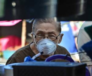A woman wears a protective face mask to prevent the spread of the new Coronavirus, at the Agriculture Market, in Tegucigalpa, on March 14, 2020. - Honduran government has prohibited citizens from Europe, China, Iran, and South Korea the entrance to the country. (Photo by ORLANDO SIERRA / AFP)