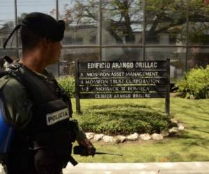 A policeman stands guard outside Mossack Fonseca headquarters as members of the Construction Workers Union demonstrate, at Panama city on April 13, 2016. Police on Tuesday raided the headquarters of the Panamanian law firm whose leaked Panama Papers revealed how the world's wealthy and powerful used offshore companies to stash assets. / AFP PHOTO / Ed Grimaldo