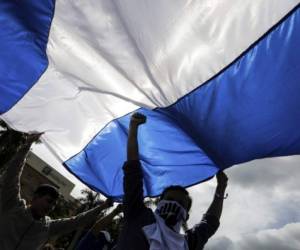 Antigovernment protesters hold a nicaraguan flag and yell slogans in front of a riot police line during the 71st International Celebration of Human Rights in Managua on December 10, 2019 (Photo by INTI OCON / AFP)