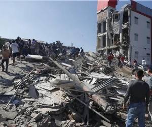 <i>Personas caminan sobre los escombros de un edificio colapsado este lunes, en Cali (Colombia). EFE/ Ernesto Guzmán</i>
