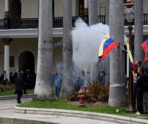 Employees of the National Assembly and members of the press run as Supporters of Venezuelan President Nicolas Maduro storm the building in Caracas on July 5, 2017 as opposition deputies hold a special session on Independence Day.A political and economic crisis in the oil-producing country has spawned often violent demonstrations by protesters demanding President Nicolas Maduro's resignation and new elections. The unrest has left 91 people dead since April 1. / AFP PHOTO / Juan BARRETO