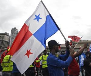 <i>Un hombre sostiene una bandera panameña durante una protesta contra un contrato minero, que se está debatiendo en el parlamento, frente a la Asamblea Nacional en la Ciudad de Panamá el 20 de octubre de 2023. FOTO LUIS ACOSTA / AFP</i>