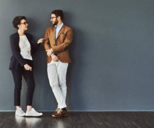 Shot of two designers having a conversation while leaning against a wall