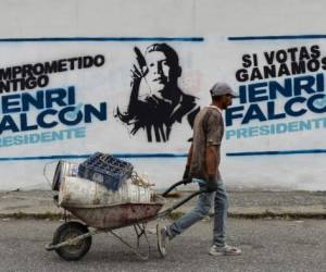 Un trabajador pasa frente a propaganda de la oposición venezolana del candidato, Henri Falcon, en Barquisimeto, Venezuela. / AFP PHOTO / Luis ROBAYO