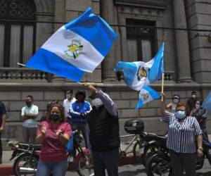 People flutter Guatemalan flags during a protest to demand Guatemalan President Alejandro Giammattei to end confinement measures imposed since March against the spread of the new coronavirus and prevent a possible collapse of the economy, outside the Congress building in Guatemala City on June 18, 2020. (Photo by Johan ORDONEZ / AFP)