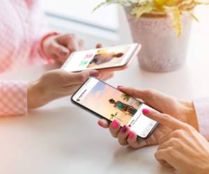 Two unrecognisable Caucasian ethnicity females using their mobile phones together