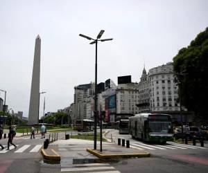 <i>Personas y autobuses pasan por la Avenida 9 de Julio y el Obelisco en Buenos Aires el 13 de diciembre de 2023. FOTO LUIS ROBAYO / AFP</i>
