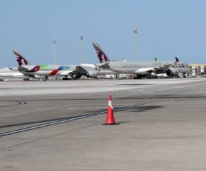 Qatar Airways aircraft Airbus A350-941 (L, R) and Boeing 777-3DZ (C) are seen on the tarmac at Hamad International Airport in the Qatari capital Doha on April 1, 2020. (Photo by KARIM JAAFAR / AFP)