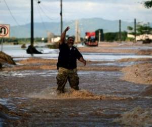 Two locals chat while standing nearby the flooded road to San Pedro Sula, following the passage of Hurricane Eta, near the locality of Campin, 240km north of Tegucigalpa, on November 7, 2020. - Scores of people have died or remain unaccounted for as the remnants of Hurricane Eta unleashed floods and triggered landslides on its deadly march across Central America. (Photo by Orlando SIERRA / AFP)