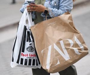 <i>Un comprador usa un iPhone de Apple mientras lleva bolsas de compras de Foot Locker y Zara mientras camina por Third Street Promenade en Santa Mónica, California, el 20 de marzo de 2023. FOTO Patrick T. Fallon / AFP</i>