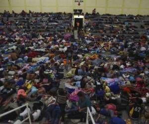 Honduran migrants heading to the United States, rest at a gymnasium of a Catholic church in Chiquimula, Guatemala, on October 16, 2018. - A migrant caravan set out on October 13 from the impoverished, violence-plagued country and was headed north on the long journey through Guatemala and Mexico to the US border. President Donald Trump warned Honduras he will cut millions of dollars in aid if the group of about 2,000 migrants is allowed to reach the United States. (Photo by Orlando ESTRADA / AFP)