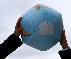 Un activista ambiental sostiene un globo inflable, que muestra el Polo Sur y la Antártida, durante una manifestación frente a la sede de las conversaciones exploratorias entre los principales miembros del partido socialdemócrata SPD, los Verdes y el partido democrático libre FDP el 15 de octubre de 2021, en Berlín. FOTO CHRISTOF STACHE / AFP