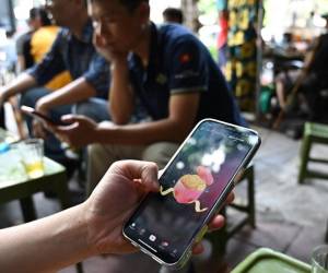 <i>Un hombre mira la plataforma de redes sociales TikTok en su teléfono móvil en Hanoi el 6 de octubre de 2023. FOTO HANÓI, VIETNAM</i>