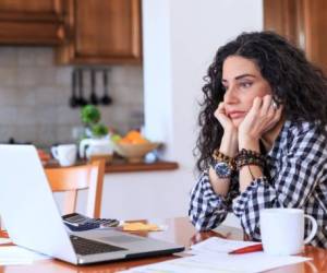 Worried young woman sitting at home, making home finaces.