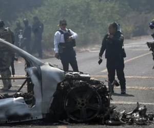Integrantes de la policía de Morelia y del ejército trabajan en la zona donde fue incendiado un vehículo por presuntos integrantes del crimen organizado en Morelia (México). EFE/ Iván Villanueva