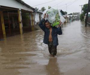 A man walks in knee-deep floodwaters carrying belongings in San Manuel, Honduras, Wednesday, Nov. 4, 2020. Eta weakened from the Category 4 hurricane to a tropical storm after lashing the Caribbean coast for much of Tuesday, its floodwaters isolating already remote communities and setting off deadly landslides. (AP Photo/Delmer Martinez)