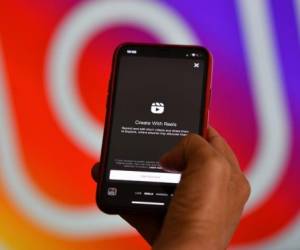 This illustration picture shows Instagram's new video feature 'Reels' on a smartphone in front of a screen showing an Instagram logo, on August 6, 2020 in Los Angeles. - Instagram on August 5 added a new short-form video feature to the image-focused platform in a direct challenge to TikTok. 'Reels' lets users record videos of up to 15 seconds and provides tools for editing, audio and effects, according to the Facebook-owned company. (Photo by Chris DELMAS / AFP)