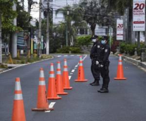 National Civil Police officers verify if vehicles have authorization to circulate and warn about the new national quarantine in the tourist 'Zona Rosa' as a measure to prevent the spread of the new coronavirus, COVID-19, at a checkpoint in San Salvador on March 22, 2020. - El Salvador's president announced the country would be placed under a 30-day quarantine on Saturday to prevent the spread of coronavirus. (Photo by Yuri CORTEZ / AFP)