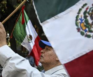 <i>Personas con banderas mexicanas protestan frente a la embajada de Ecuador en la Ciudad de México el 6 de abril de 2024, tras la ruptura de relaciones diplomáticas entre los dos países. FOTO Yuri CORTEZ/AFP</i>