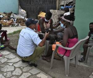 Un policía municipal habla con migrantes haitianos mientras esperan que la oficina de migraciones les dé un resguardo para continuar su camino en una caravana rumbo a Estados Unidos, en el municipio de Trojes, departamento de El Paraíso, Honduras, en la frontera con Nicaragua, el 21 de abril. , 2021. - La vicealcaldesa de Trojes, Dinora Sandoval, dijo a la AFP que un promedio de 400 personas provenientes de países africanos como Costa de Marfil, Ghana y Senegal, haitianos, cubanos y otros ingresan diariamente al municipio. (Foto de Orlando SIERRA / AFP)