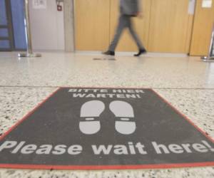 A signreading 'PLease wait here!' is fixed on the floor of the corona vaccination center at the Robert Bosch hospital in Stuttgart, southern Germany, on December 10, 2020, amid the new coronavirus COVID-19 pandemic. - The vaccination center is currently under construction and will have a capacity of 1500 vaccinations per day when it starts. (Photo by THOMAS KIENZLE / AFP)