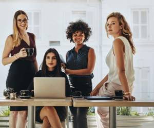 Portrait of four successful young businesswomen together in office. Group of multi-ethnic businesswomen looking at camera.