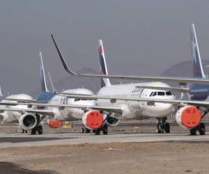 Aircrafts of Latam airline sit on the tarmac at Santiago International Airport, in Santiago, on April 20, 2020 during the new coronavirus, COVID-19, pandemic. - Latin America's biggest airline, the Brazilian-Chilean group LATAM, announced last Friday that the 95% reduction of its passenger operations announced in April will be extended until May due to the coronavirus crisis, which will cause a deeper impact than expected. (Photo by MARTIN BERNETTI / AFP)