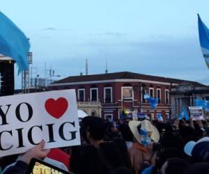 People hold signs during a demonstration outside the headquarters of the UN International Commission Against Impunity, CICIG, to acknowledge its performance against corruption, in Guatemala City on August 31, 2019. - The Cicig's mandate comes to an end next Tuesday after President Jimmy Morales broke his promise to extend it for two more years. (Photo by Johan ORDONEZ / AFP)