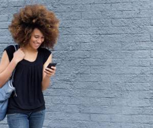 Portrait of smiling woman walking and looking at mobile phone