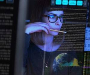 Stock image of a beautiful young woman studying a see through computer screen & contemplating.