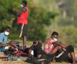 Haitian migrants sit on the grass at a migrant camp amid the new coronavirus pandemic in San Vicente, Darien province, Panama, Tuesday, Feb. 9, 2021. Panama is allowing hundreds of migrants stranded because of the pandemic, to move to the border with Costa Rica after just reopening its land borders. (AP Photo/Arnulfo Franco)