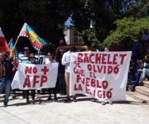 Demonstrators hold a Chilean national flag and a shield are seen near a police vehicle during a protest against the government in Santiago on November 29, 2019. - Furious Chileans have since October 18 been protesting social and economic inequality, and against an entrenched political elite that comes from a small number of the wealthiest families in the country, among other issues. (Photo by Martin BERNETTI / AFP)