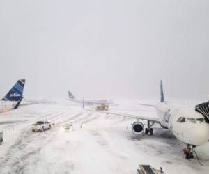 Avones de JetBlue parqueados -y cubiertos de nieve- esperan a que mejore el tiempo en la terminal 5 del aeropuerto internacional John F. Kennedy. Foto AFP
