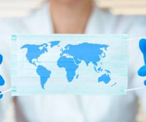 Laboratory worker holding protective mask with world map