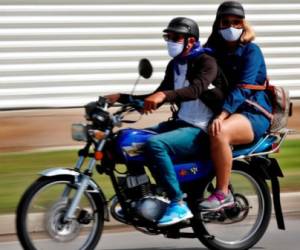 Dos personas con tapabocas se movilizan en una moto, este lunes en La Habana (Cuba). EFE/Ernesto Mastrascusa