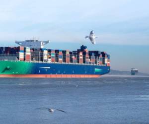 Two large Container ships leaving the port of Hamburg on the river Elbe, Germany. Ice floe on the river and seagulls in the air.