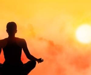 women meditating on high mountain in sunset background