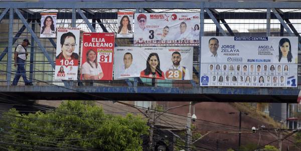 <i>Un hombre camina sobre un puente que tiene propaganda política este domingo, en Tegucigalpa (Honduras). Los precandidatos a cargos de elección popular que participarán en las elecciones primarias e internas de Honduras, programadas para el 9 de marzo, queman sus últimos cartuchos para conseguir votos previo a las elecciones generales de noviembre. EFE/ Gustavo Amador</i>