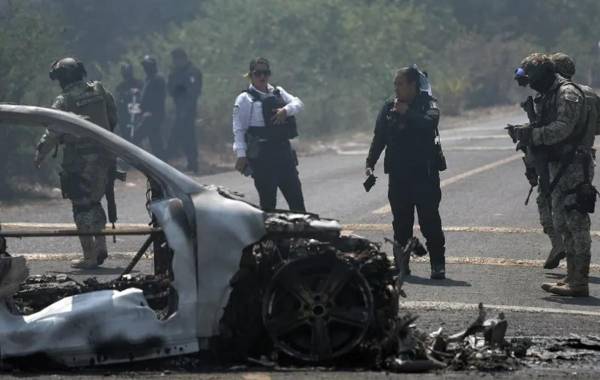 Integrantes de la policía de Morelia y del ejército trabajan en la zona donde fue incendiado un vehículo por presuntos integrantes del crimen organizado en Morelia (México). EFE/ Iván Villanueva