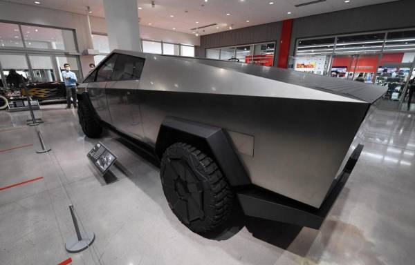 <i>Los visitantes que usan cubiertas faciales ven el Tesla Cybertruck en el recientemente reabierto Petersen Automotive Museum en los Ángeles, California, el 1 de julio de 2020. FOTO Robyn Beck/AFP</i>