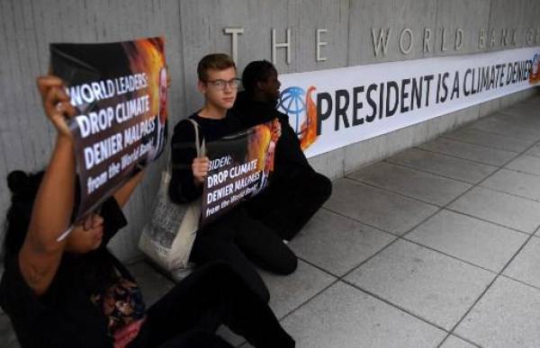 Los activistas exhiben una pancarta que llama al presidente del Banco Mundial, David Malpass, un “negador del clima”, frente a la sede del Banco Mundial en Washington, DC, el 22 de septiembre de 2022. - Los grupos climáticos pidieron que se destituyera a Malpass después de que se negara varias veces para decir si creía que las emisiones provocadas por el hombre contribuyeron al calentamiento global el 21 de septiembre. (Foto de OLIVIER DOULIERY / AFP)