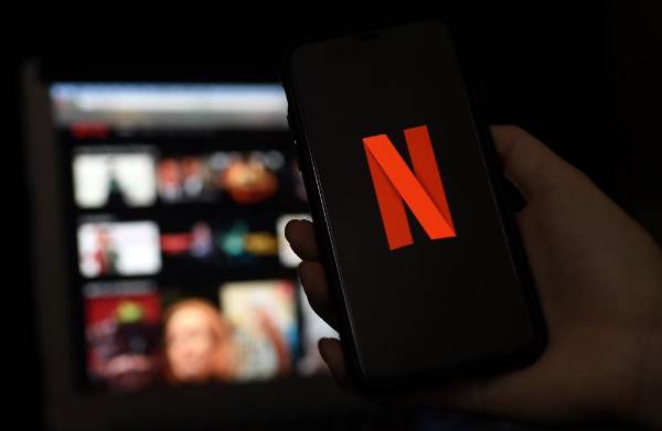 In this photo illustration a computer and a mobile phone screens display the Netflix logo on March 31, 2020 in Arlington, Virginia. (Photo by Olivier DOULIERY / AFP)