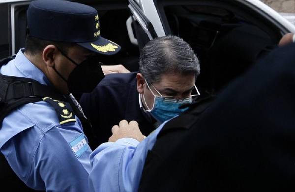 <i>Escolta policial al expresidente Juan Orlando Hernández a su llegada al Palacio de Justicia para asistir a su primera audiencia de extradición en Tegucigalpa, el 16 de febrero de 2022. FOTO ARCHIVO / AFP</i>