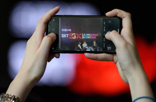 <i>Un miembro de la audiencia toma una fotografía durante un evento de lanzamiento de SK Telecom para la red móvil 5G de la compañía, en Seúl, el 3 de abril de 2019.FOTO Ed JONES/AFP</i>