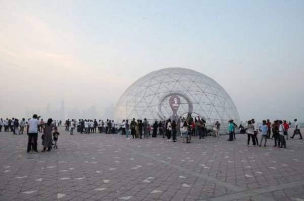 La gente se reúne en la cúpula que alberga el reloj de cuenta regresiva de la Copa Mundial de la FIFA Qatar 2022 cuando marca cien días, en la capital, Doha, el 12 de agosto de 2022. - La FIFA y los organizadores de Qatar calcularon el costo de adelantar el inicio de la Copa del Mundo en un día. mientras lanzaban la cuenta regresiva de 100 días para el evento. (Foto de Mustafa ABUMUNES / AFP)