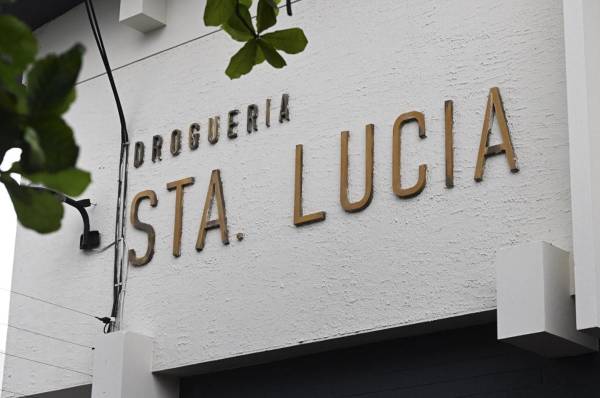 <i>Vista de la droguería Santa Lucía, propiedad del expresidente salvadoreño Alfredo Cristiani, acusado de corrupción, mientras policías la custodian luego de que el presidente Nayib Bukele anunciara un operativo para allanar las propiedades de Cristiani en San Salvador el 2 de junio de 2023. FOTO MARVIN RECINOS / AFP</i>