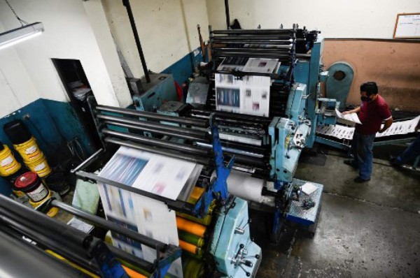 A printing worker checks the last print edition of the newspaper La Hora in Guatemala City on November 12, 2021. - After 101 years, the evening newspaper La Hora de Guatemala printed its last paper edition on Friday, amid the nostalgia of workers and readers. As of Saturday, only an online edition will be avilable. (Photo by Johan ORDONEZ / AFP)