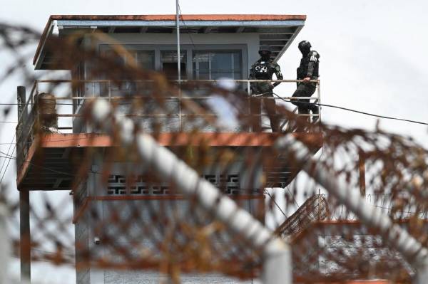 <i>Elementos de la Policía Militar de Orden Público (PMOP) vigilan desde una torre de vigilancia la presentación a la prensa de armas, municiones, drogas, teléfonos móviles y otros elementos incautados durante un operativo en la Penitenciaría Nacional “Francisco Morazán” en el penal de Tamara, 25 km al norte de Tegucigalpa, el 26 de junio de 2023. (Foto de Orlando SIERRA / AFP)</i>