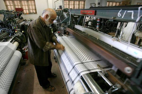 <i>Una persona trabaja junto a un telar en una fábrica textil. Imagen de archivo. EFE/Abed Al Hashlamoun</i>